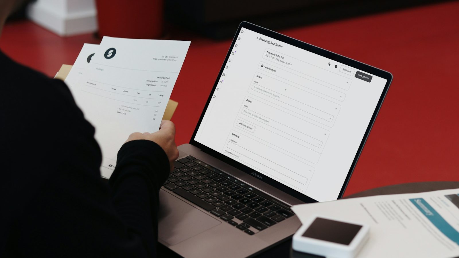 A person checking printed invoices beside a laptop open on an invoicing screen, comparing what development work costs.