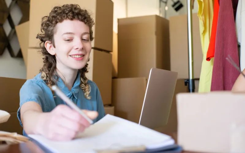 Brand founder ticking off a Shopify SEO checklist among product boxes before launch
